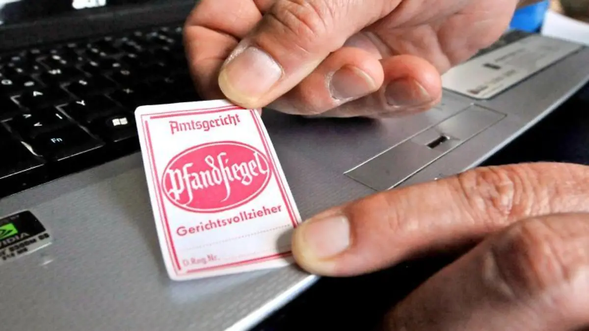 Pfandsiegel wird auf einen Laptop geklebt
