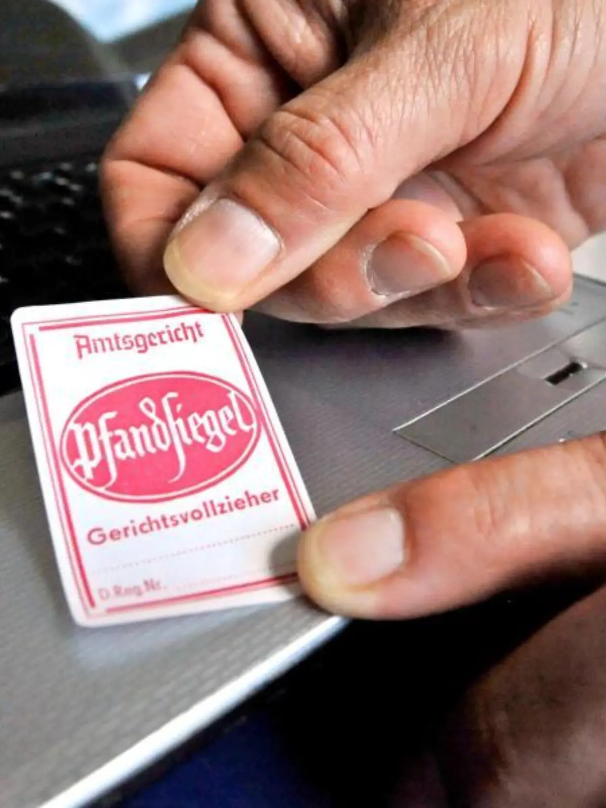 Pfandsiegel wird auf einen Laptop geklebt