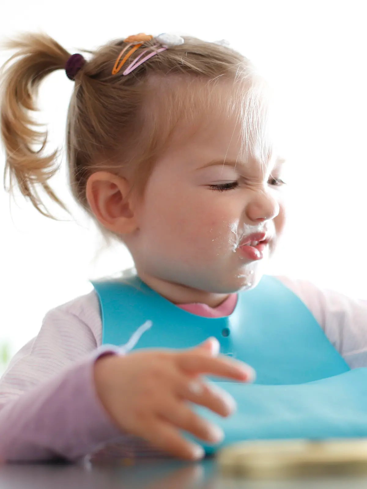 Little girl toddler picking her food, making faces. Childhood problems, picky eater, eating habits, terrible two concept.