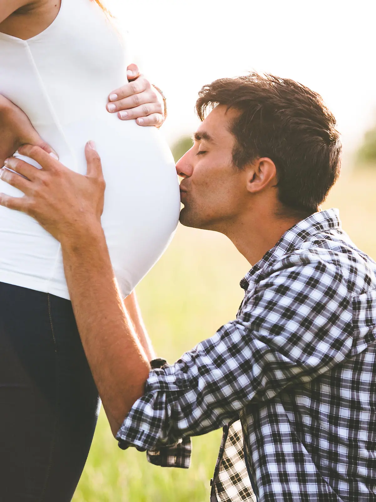 Young man kissing the belly of his pregnant woman
