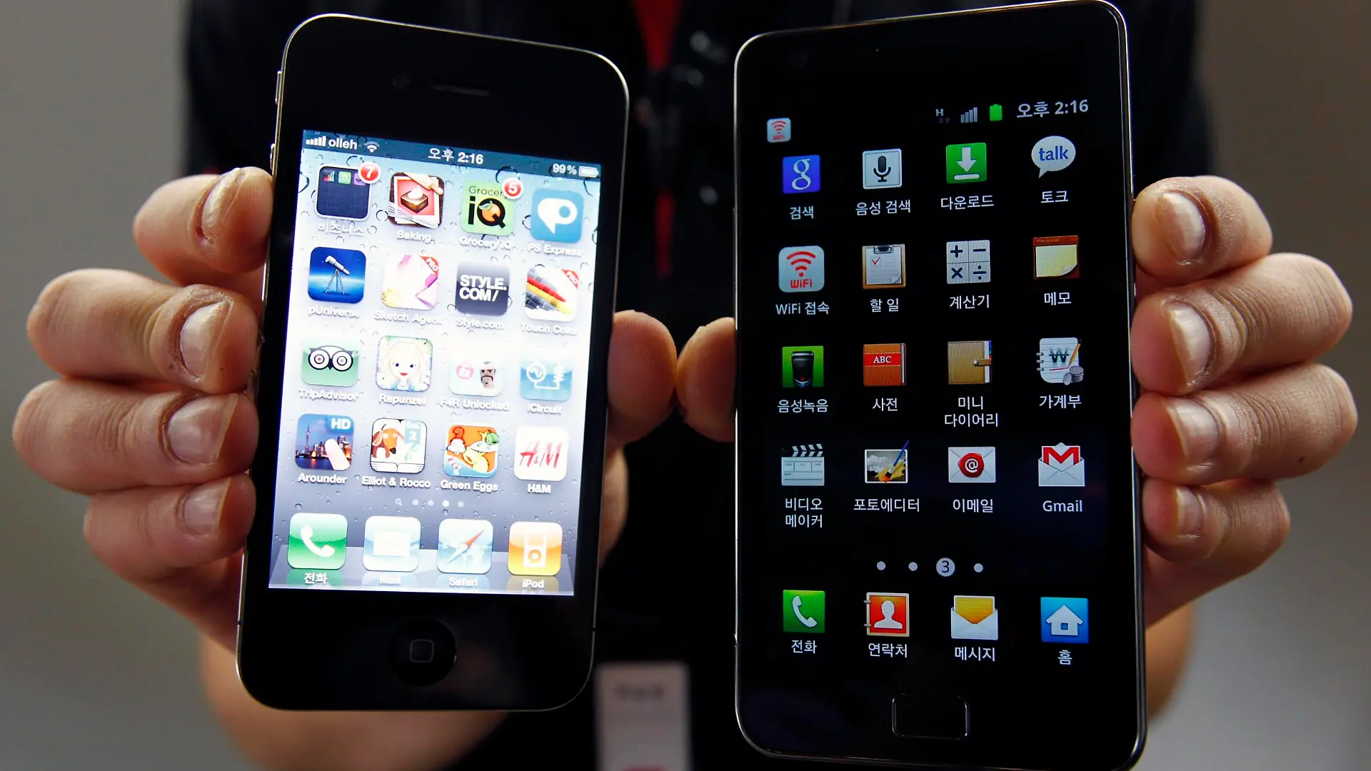 File picture shows an employee of South Korean mobile carrier KT holding an Apple Inc's iPhone 4 (L) smartphone and a Samsung Electronics' Galaxy S II smartphone as he poses for photographs at a registration desk at KT's headquarters in Seoul, August 25, 2011. Samsung Electronics lost a bid to overturn a ruling barring its local unit from selling its Galaxy 10.1 tablets in Germany, handing a symbolic legal victory to Apple Inc in efforts to keep its lead spot in the tablet computer market. A higher regional court said on January 31, 2012 that Samsung may not sell the older version of its Galaxy tablet in Europe's biggest economy. Apple is fighting several rival makers of smartphones and tablet PCs in courts worldwide over intellectual property. Picture taken August 25, 2011.  REUTERS/Jo Yong-Hak/File (SOUTH KOREA - Tags: CRIME LAW BUSINESS POLITICS)