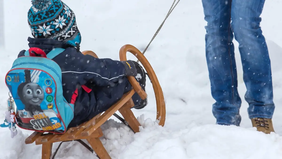 Ein Vater zieht am 10.12.2012 in Ilmenau (Thüringen) sein Kind auf einem Schlitten über einen Schneeberg. Heftige Schneefälle und Schneeverwehungen machen im Thüringer Wald Menschen und Straßenverkehr Probleme, weitere starke Schneefälle werden vorhergesagt. Foto: Michael Reichel/dpa  +++(c) dpa - Bildfunk+++
