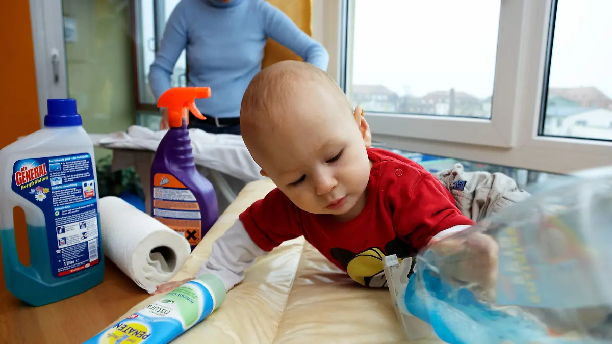 Während die Mutter mit Bügeln der Hausarbeit nach geht entdeckt ein Kleinkind seine Umwelt und greift nach einer Flasche mit Reinigungsmitteln, die um seinen Wickeltisch aufgestellt sind, aufgenommen in Leipzig am 01.12.2006 (gestelltes Illustrationsfoto zum Thema Gefahr im Haushalt für Kinder) Foto: Jörg Lange +++(c) dpa - Report+++