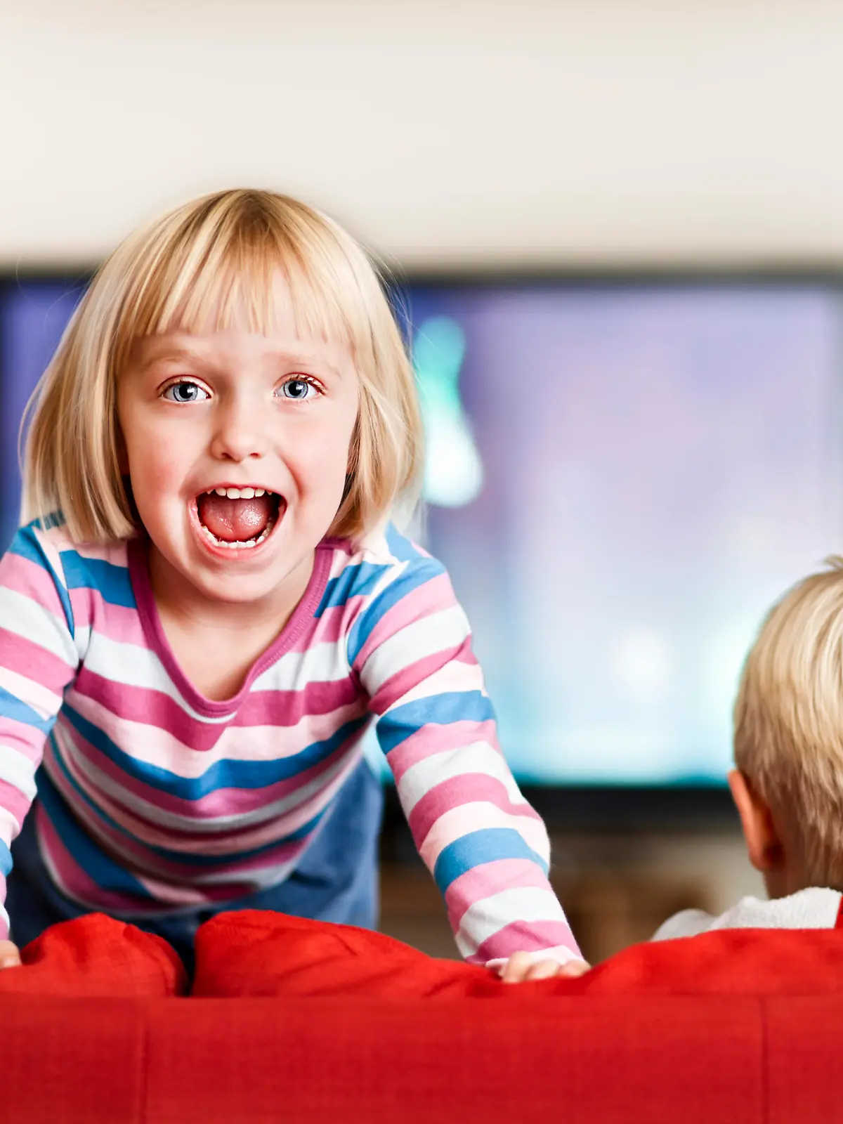 While her big brother watches television, this excited three-year-old simply cannot sit still! Shot with Canon EOS 1Ds Mark III. 