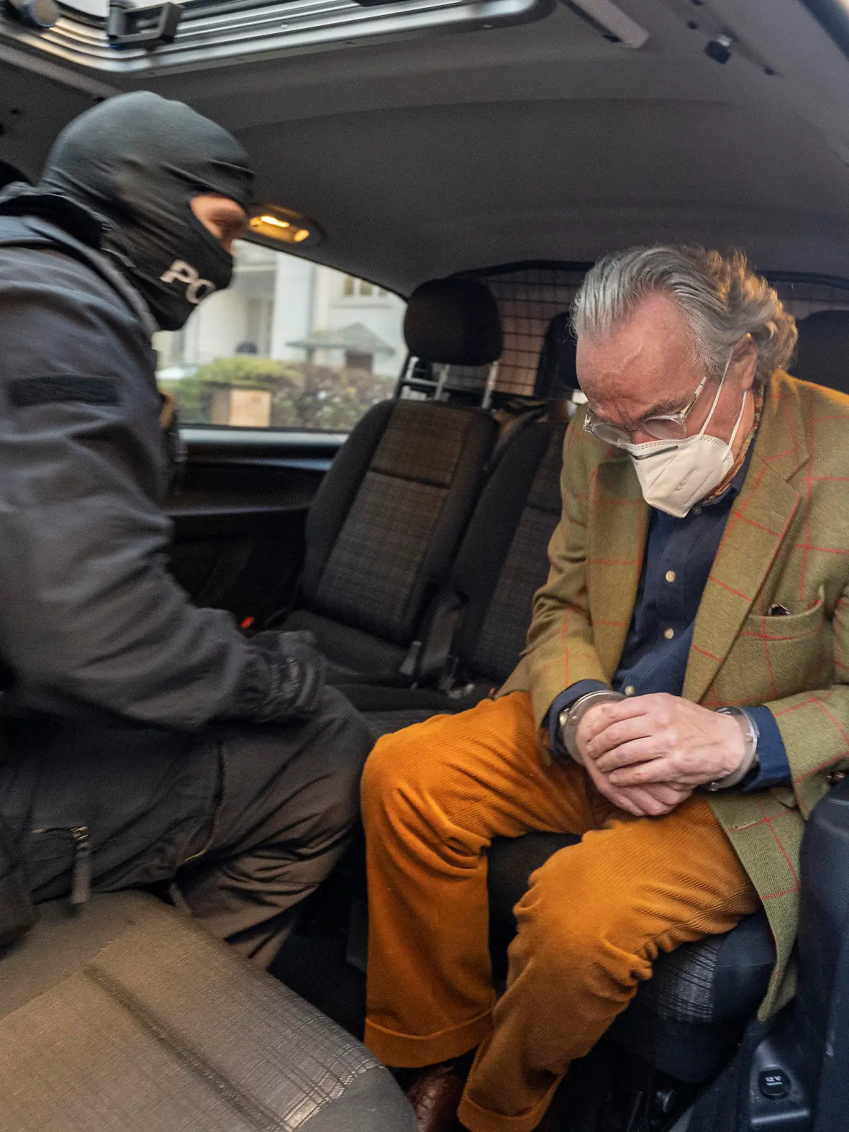 07.12.2022, Hessen, Frankfurt/Main: Bei einer Razzia gegen sogenannte «Reichsbürger» sitzt ein vermummter Polizist, nach der Durchsuchung eines Hauses, mit dem festgenommenen Heinrich XIII Prinz Reuß (r) in einem Polizeifahrzeug. Dieser trägt dabei Handschellen. Die Bundesanwaltschaft hat am Mittwochmorgen mehrere Menschen aus der sogenannten Reichsbürgerszene im Zuge einer Razzia festnehmen lassen. Zahlreiche Beamte seien in mehreren Bundesländern im Einsatz, sagte eine Sprecherin der Karlsruher Behörde . Foto: Boris Roessler/dpa +++ dpa-Bildfunk +++