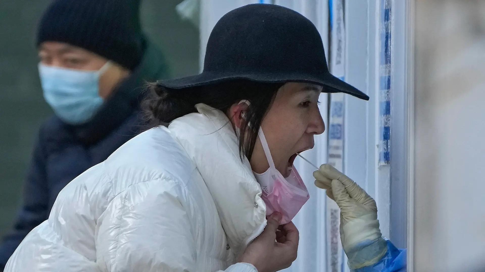 FILE- A woman has her routine COVID-19 throat swab at a coronavirus testing site in Beijing, Sunday, Dec. 4, 2022. China on Wednesday, Dec. 7, 2022, announced new measures rolling back COVID-19 restrictions, including limiting lockdowns and testing requirements. (AP Photo/Andy Wong, File)