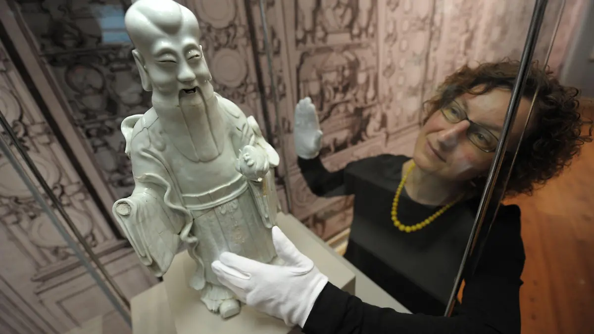 Heike Pöppelmann, Direktorin des Braunschweigischen Landesmuseums, betrachtet am Donnerstag (31.03.2011) die gesprungene Porzellan-Figur eines Chinesen aus dem 18. Jahrhundert. Die Figur ist Teil der Ausstellung "Luxus in Scherben" im Landesmuseum in Braunschweig, die vom 03.04. bis 03.07.2011 zu sehen ist. Foto: Peter Steffen dpa/lni (Zu lni vom 01.04.2011) +++(c) dpa - Bildfunk+++