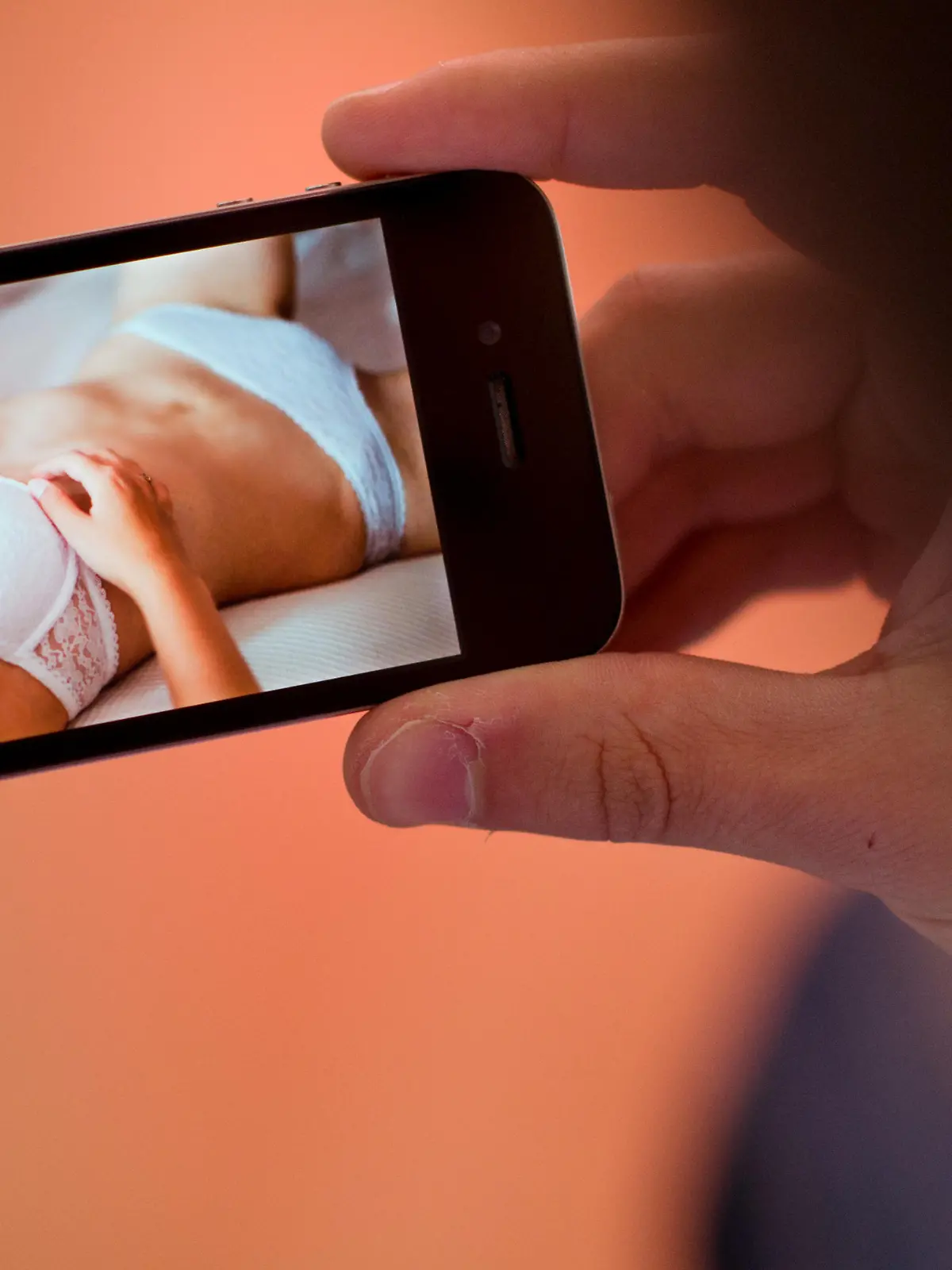 ILLUSTRATION - Ein junger Mann hält am 31.10.2013 in Hannover (Niedersachsen) ein Smartphone, auf dem ein erotisches Foto einer jungen erwachsenen Frau zu sehen ist. Zahlreiche Schulleiter aus Cloppenburg warnen in einem gemeinsamen Elternbrief vor dem neuen Trend «Sexting». Dabei versenden Jugendliche erotische Fotos oder Nacktbilder von sich per Smartphone an Freunde oder laden sie in sozialen Netzwerken hoch. Foto: Julian Stratenschulte/dpa