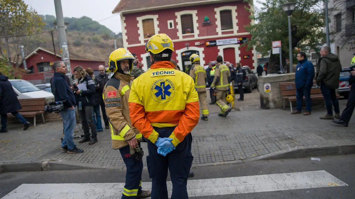 07.12.2022, Spanien, Manresa: Ein Feuerwehrmann (l) und ein Rettungssanitäter stehen vor dem Bahnhof Montcada i Reixac nach dem Zusammenstoß zweier Züge. Beim Zusammenprall von zwei Vorortzügen der Millionenmetropole Barcelona sind am Mittwochmorgen rund 150 Passagiere verletzt worden. Foto: Lorena Sopêna/EUROPA PRESS/dpa +++ dpa-Bildfunk +++