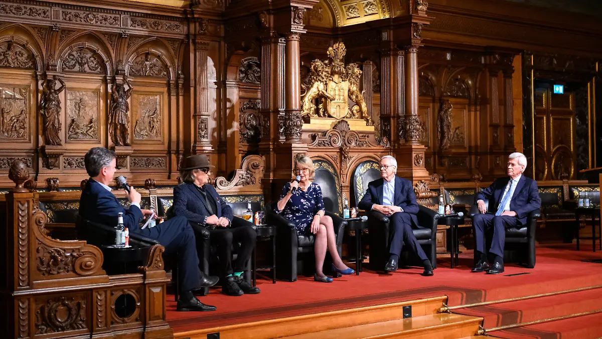 06.12.2022, Hamburg: Der Moderator des Abends Lars Haider (l-r), Chefredakteur Hamburger Abendblatt, mit Rocksänger Udo Lindenberg, Autorin Kirsten Boie, Choreograf John Neumeier und Unternehmer Michael Otto auf der Bühne im Großen Festsaal des Rathauses. Auf Einladung des Übersee-Clubs kommen vier Ehrenbürger der Stadt zu einem Gespräch über die Zukunft von Hamburg zusammen. Foto: Jonas Walzberg/dpa +++ dpa-Bildfunk +++