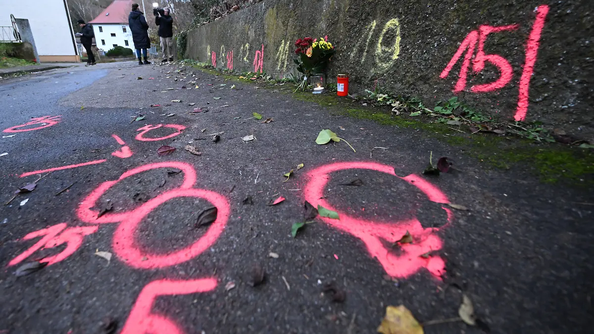 05.12.2022, Baden-Württemberg, Illerkirchberg: Blumen und Kerzen stehen an Markierungen der Spurensicherung der Polizei an einem Tatort auf einem Weg. Zwei Mädchen wurden auf ihrem Schulweg angegriffen und schwer verletzt. Foto: Bernd Weißbrod/dpa +++ dpa-Bildfunk +++