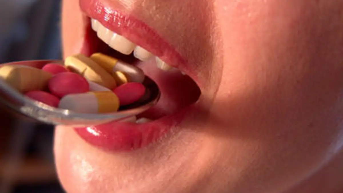 Frau nimmt Tabletten mit einem Löffel ein