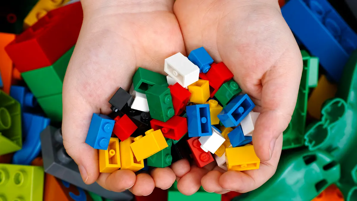 Tambov, Russian Federation - February 20, 2015 Lego Bricks in child's hands with Lego Duplo blocks and toys background. Studio shot.