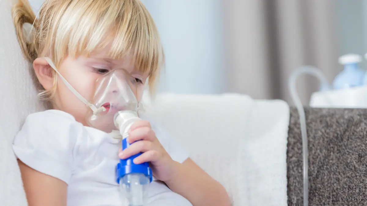 Serious little girl with cystic fibrosis receives breathing treatment.