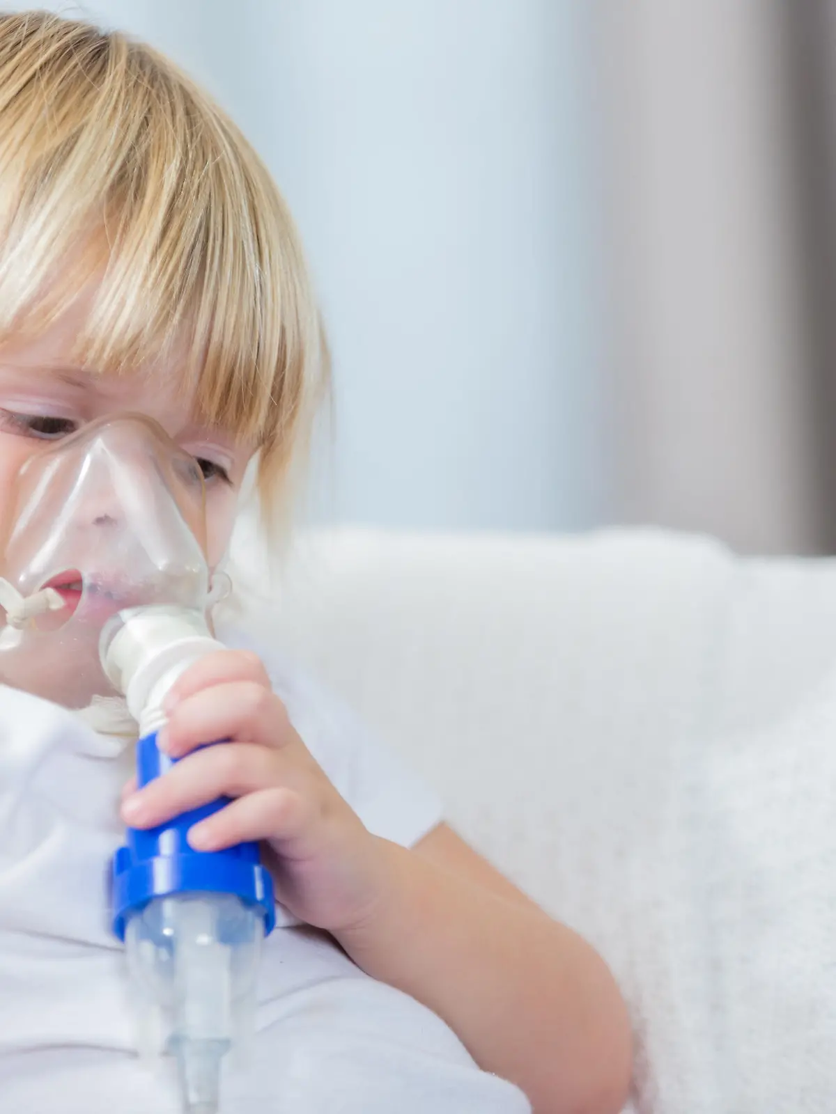 Serious little girl with cystic fibrosis receives breathing treatment.
