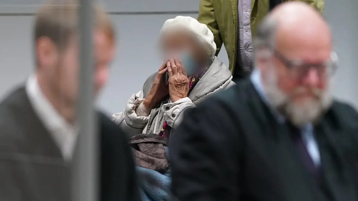 06.12.2022, Schleswig-Holstein, Itzehoe: Die Angeklagte Irmgard F. (M) wird zu Beginn des Prozesstages in den Sitzungssaal gebracht. Vorne im Bild sitzen ihre Anwälte Niklas Weber (l) und Wolf Molkentin. Der Prozess gegen die ehemalige KZ-Sekretärin vor dem Landgericht Itzehoe wird mit dem Plädoyer der Verteidigung fortgesetzt. Der 97-Jährigen wird Beihilfe zum Mord in über 11.000 Fällen zur Last gelegt. Foto: Marcus Brandt/dpa POOL/dpa - ACHTUNG: Die Angeklagte wurde aus rechtlichen Gründen gepixelt +++ dpa-Bildfunk +++