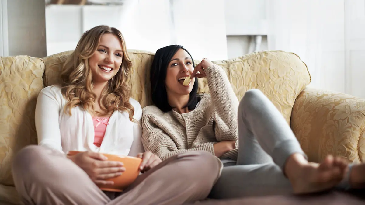 Women sitting on sofa watching a movie in a cozy loft apartment