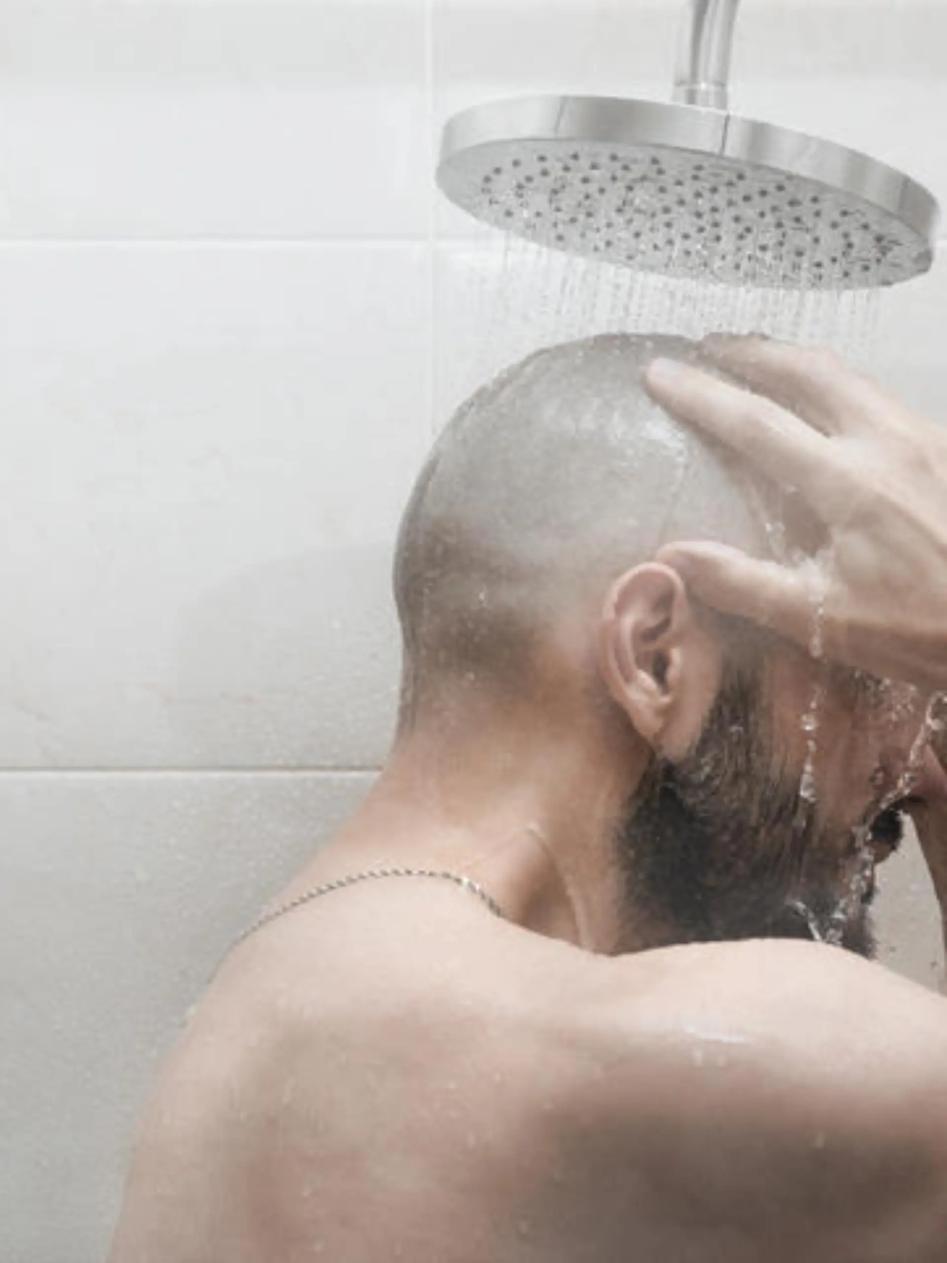A man washes in the shower. Side view