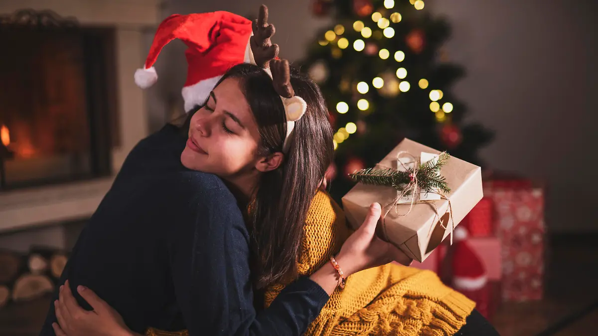 Sisters hugging during opening Christmas presents.