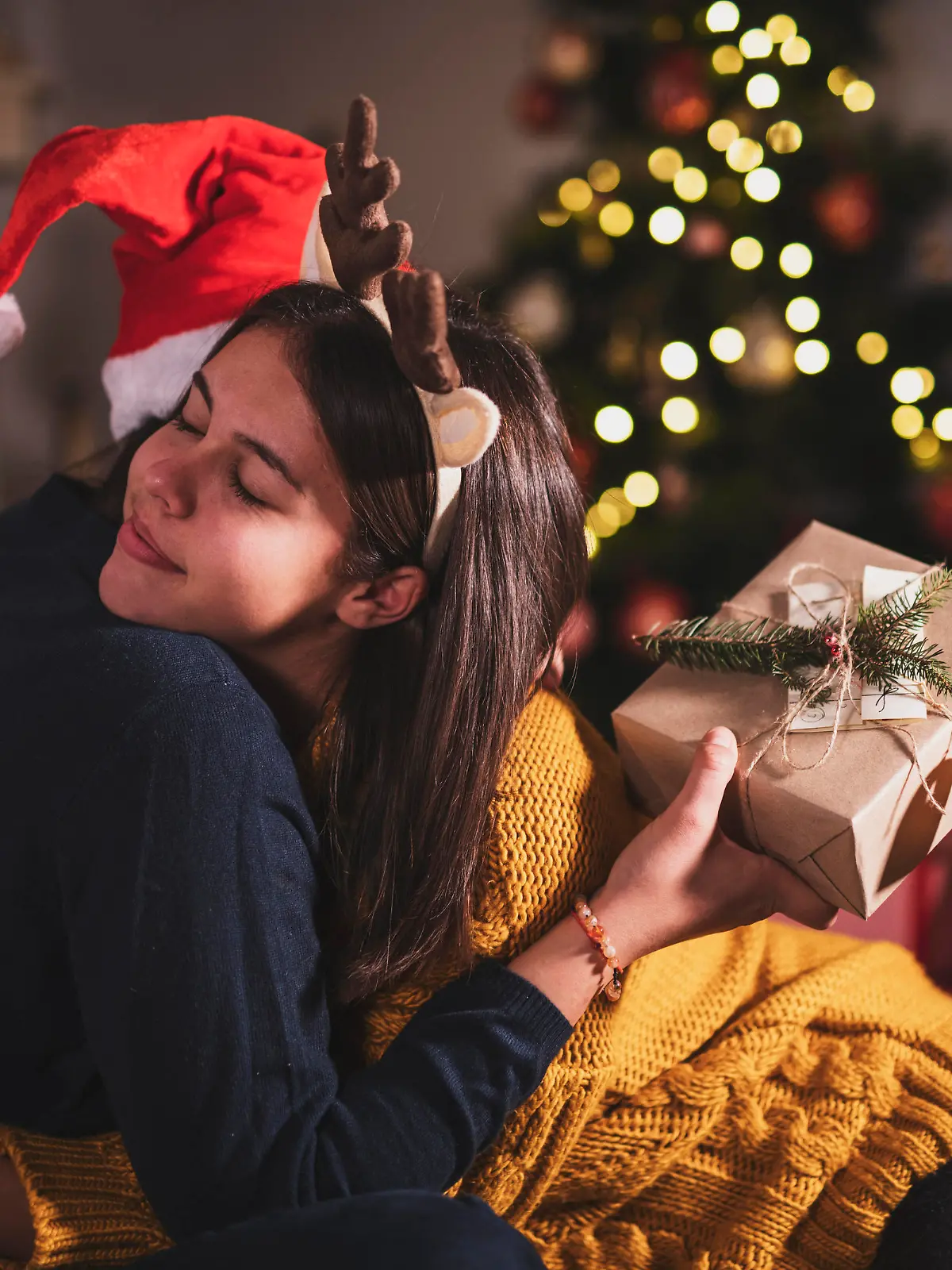 Sisters hugging during opening Christmas presents.