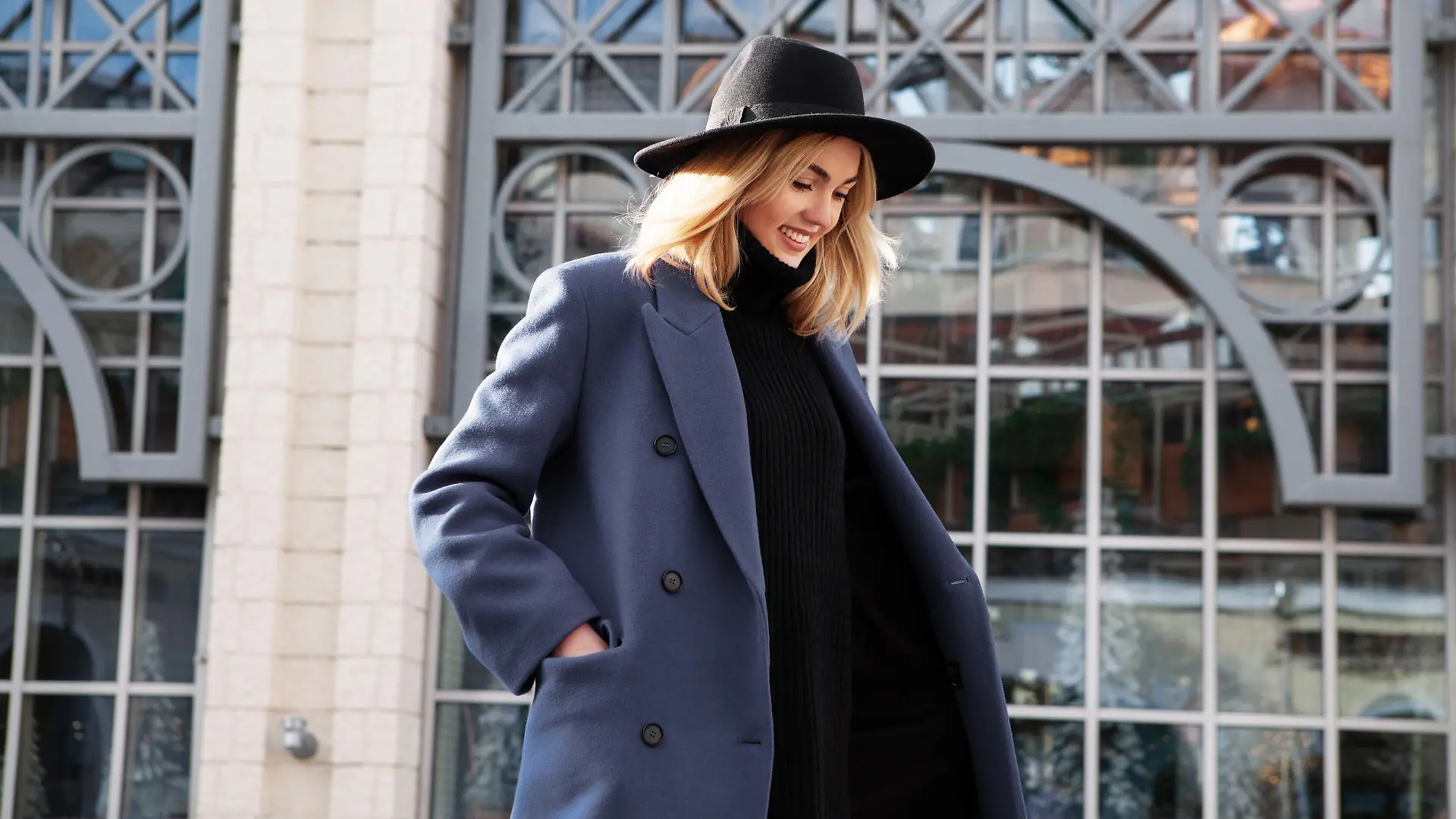 Lifestyle portrait of fashionable woman wearing winter or spring outfit, felt hat, gray wool coat, turtleneck. Outdoors. Female stylish Model smiling, walking city Street. Street fashion trend
