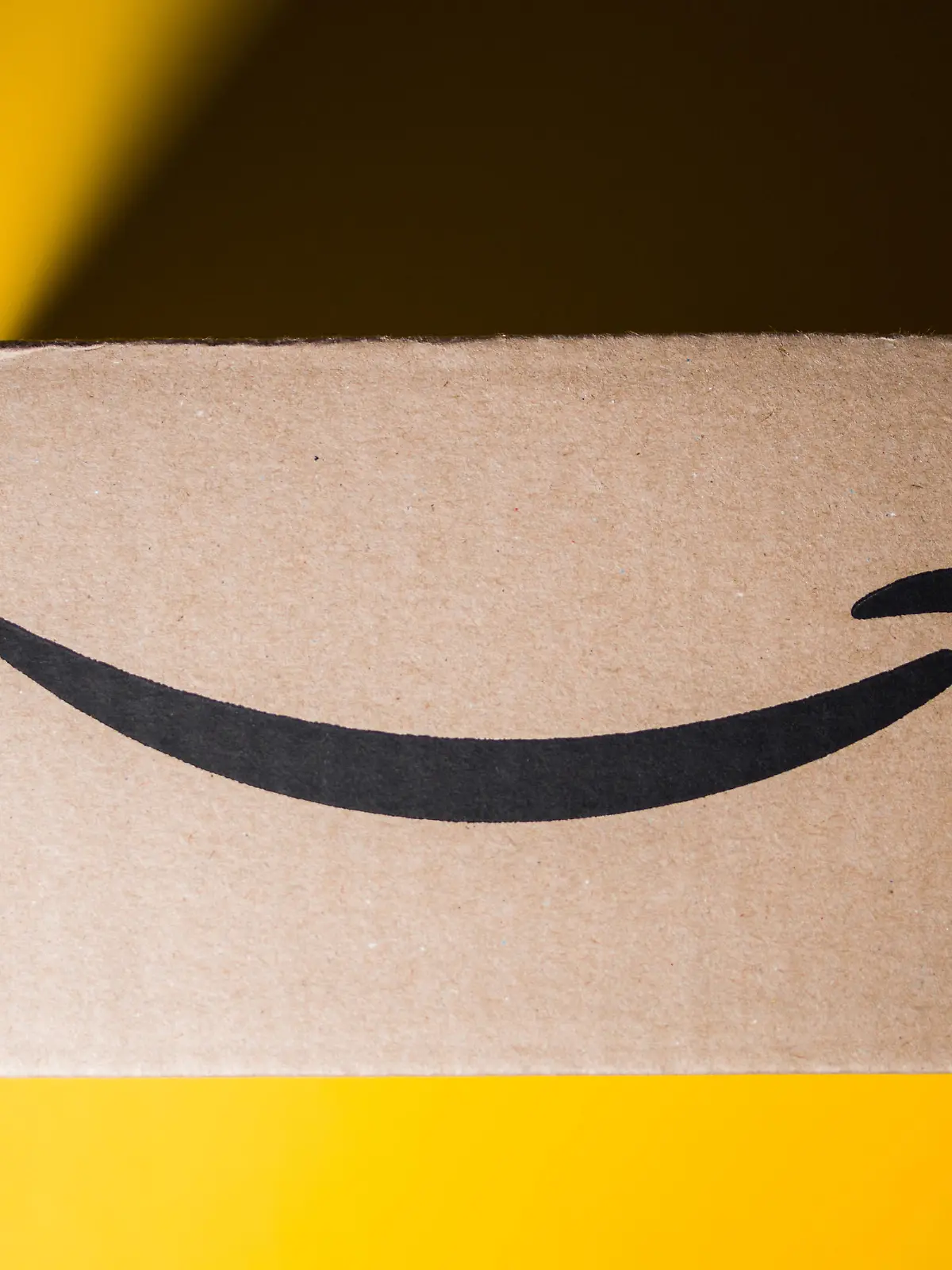 PARIS, FRANCE - SEP 28, 2018: Directly above view of New Amazon Cardboard box against yellow background. Amazon Prime is the online paid subscription service offered by Amazon.com web-commerce site