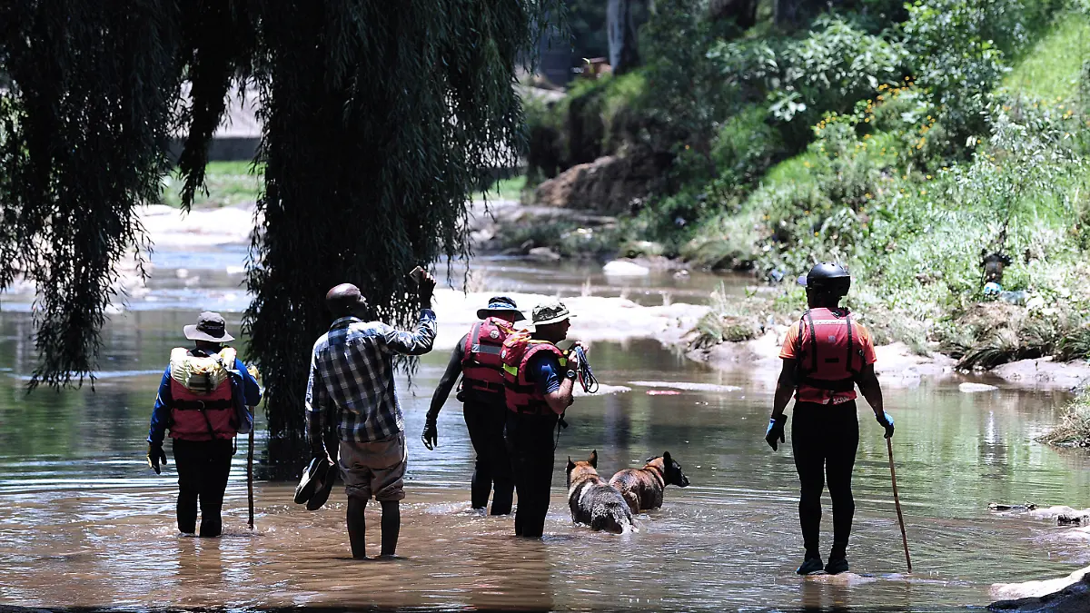 04.12.2022, Südafrika, Johannesburg: Rettungskräfte gehen mit ihren Hunden während der Rettungsarbeiten durch den Jukskei-Fluss. In einem Vorort der südafrikanischen Metropole Johannesburg sind mindestens neun Teilnehmer einer Taufzeremonie ertrunken. 33 Täuflinge, die sich am Samstag in Bramley Park am Ufer des Jukskei-Flusses versammelt hatten, seien von einer plötzlichen Sturzflut und starken Strömung überrascht worden, erklärte ein Sprecher der Rettungskräfte am Sonntag. Foto: -/AP/dpa +++ dpa-Bildfunk +++