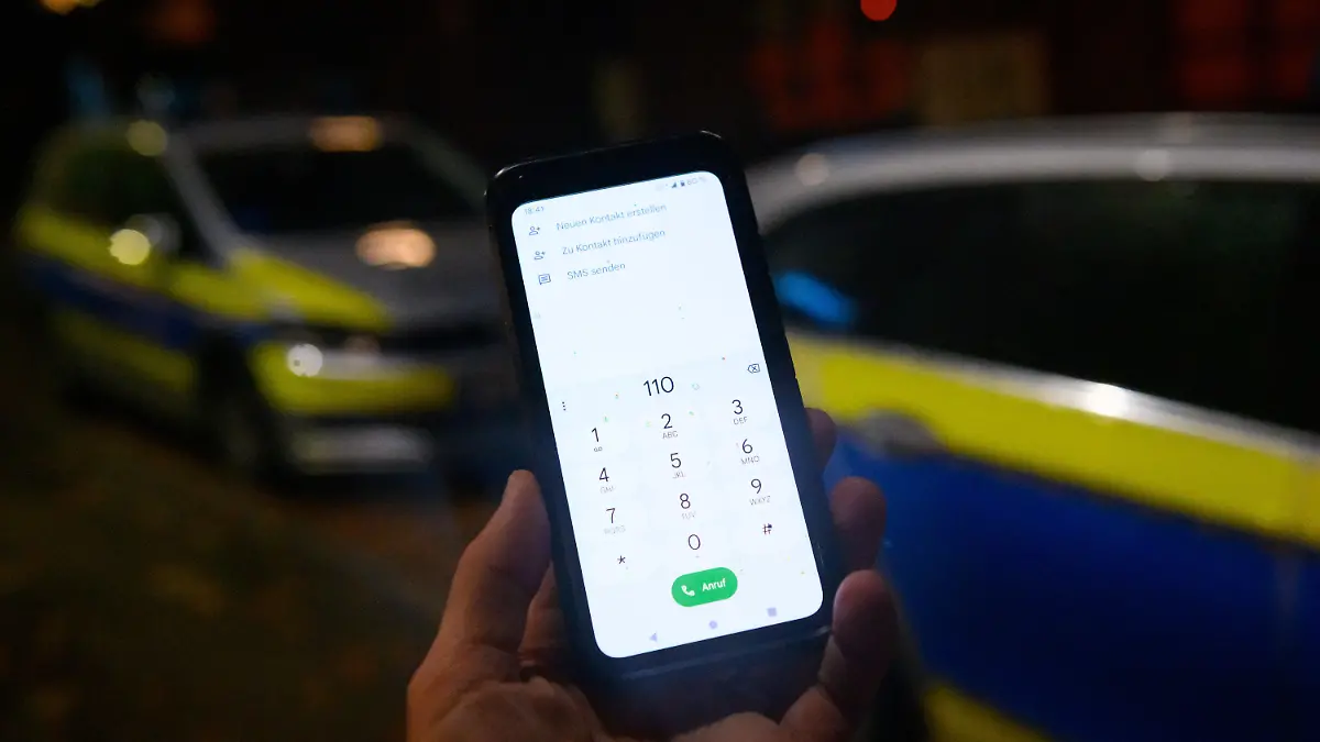 ILLUSTRATION - 17.11.2022, Hamburg: Die Notrufnummer "110" ist auf einem Smartphone eingegeben, dass vor zwei Streifenwagen gehalten wird. Wegen Störungen im Mobilfunknetz haben die Behörden in Berlin, Bremen und Hamburg am 17.11.2022 verstärkt Hinweise bekommen, dass der Notruf nicht zu erreichen sei. Foto: Jonas Walzberg/dpa +++ dpa-Bildfunk +++