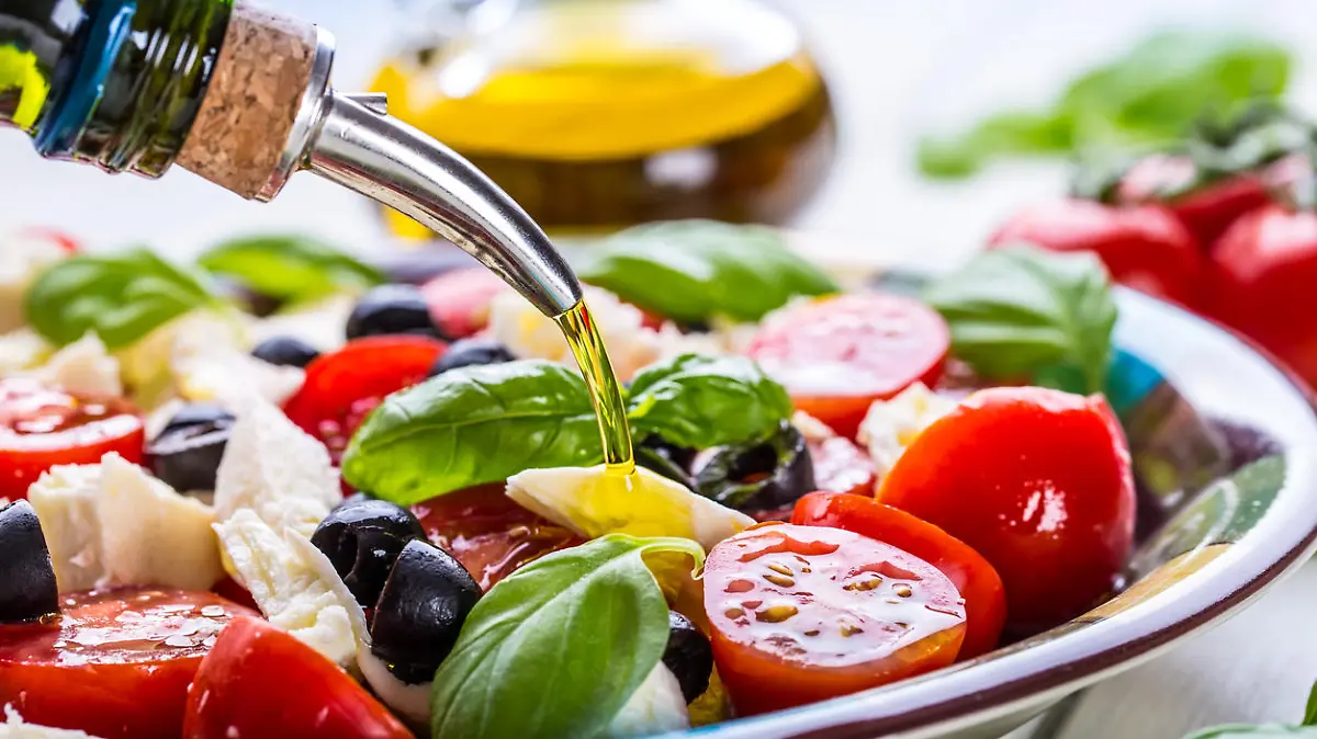 Caprese. Caprese salad. Italian salad. Mediterranean salad. Italian cuisine. Mediterranean cuisine. Tomato mozzarella basil leaves black olives and olive oil on wooden table. Recipe - Ingredients