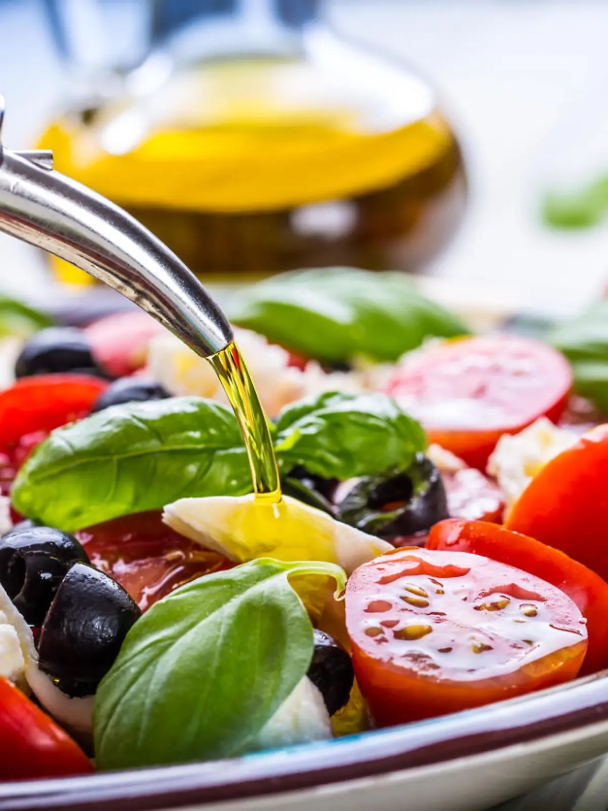 Caprese. Caprese salad. Italian salad. Mediterranean salad. Italian cuisine. Mediterranean cuisine. Tomato mozzarella basil leaves black olives and olive oil on wooden table. Recipe - Ingredients