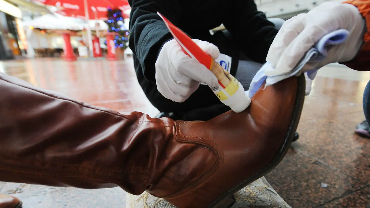 Schüler putzen am Mittwoch (24.11.2010) in Berlin mit Schuputzcreme und Lappen einen Lederstiefel. Schüler der Finow-Grundschule Berlin putzten vor dem KaDeWe Schuhe und Stiefel von Passanten und sammelten somit im Rahmen der bundesweiten Aktion der Kindernothilfe "Action!Kidz - Kinder gegen Kinderarbeit" Geld für notleidende Kinder in Haiti. Gleichzeitig lernten die Kinder höfliche Umgangsformen und auch die Überwindung von Scheu, so die Lehrerin. Foto: Tobias Kleinschmidt dpa/lbn +++(c) dpa - Bildfunk+++