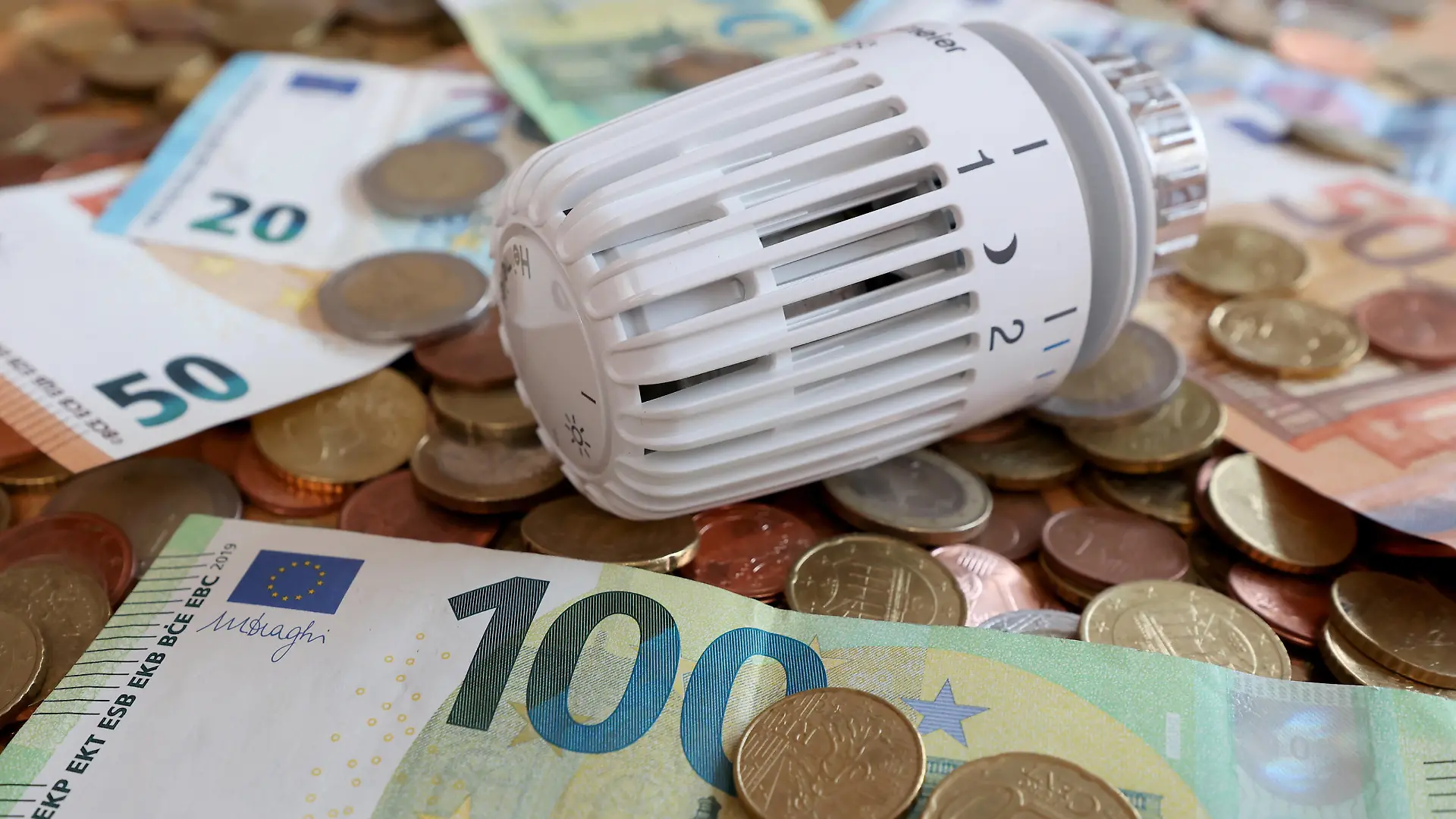 Gasumlage kommt. Gaspreisexplosion angesichts des Krieges in der Ukraine. Thermostatkopf liegt zwischen Euro Geldscheinen und Euromuenzen Euromünzen. Symbolbild zum Thema Energiekosten, Gaspreise, Gasumlage am 16.08.2022 in Siegen/Deutschland *** Gas levy comes gas price explosion in the face of war in Ukraine thermostat head lies between euro banknotes and euro coins euro coins symbol image on the subject of energy costs, gas prices, gas levy on 16 08 2022 in Siegen Germany