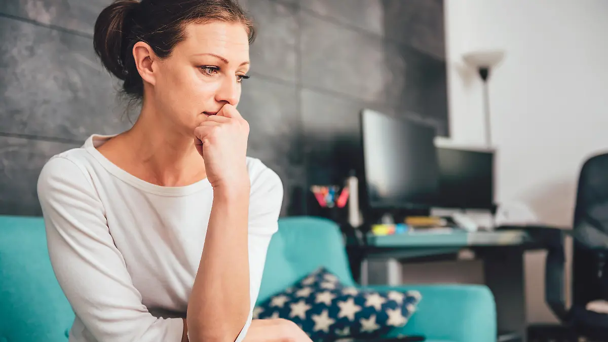 Sad woman sitting on a sofa in the living room
