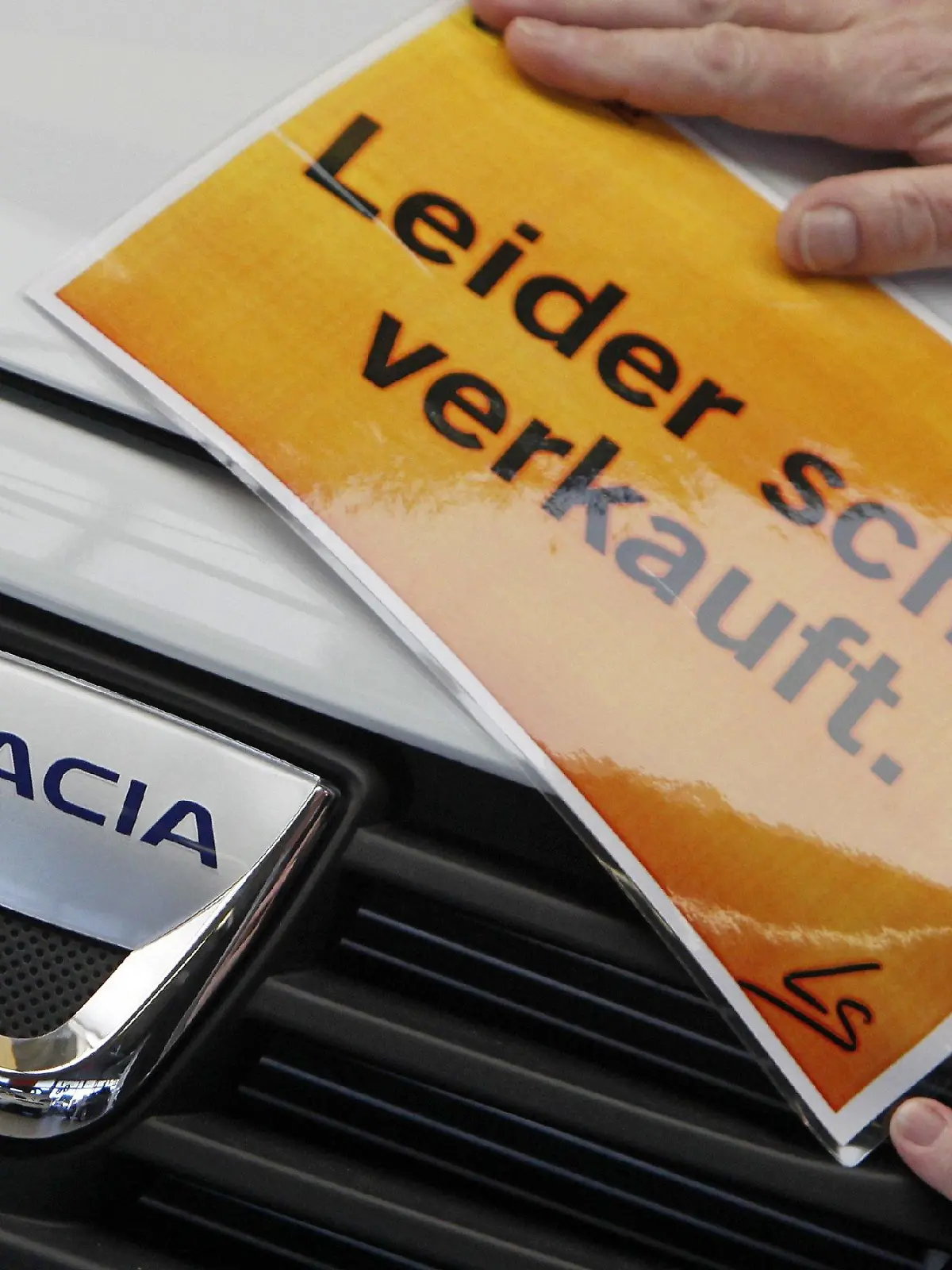 Ein Verkäufer in einem Autohaus in Leipzig befestigt ein Schild "Leider schon verkauft" an einem Dacia Sandero, aufgenommen am Donnerstag (05.02.2009). Der Wagen kostet in der Minimalvariante 7.500 Euro. Wer seinen alten Pkw verschrotten lässt und 2.500 Euro Abwrackprämie kassiert, kauft ein neues Auto damit für 5.000 Euro. Durch den Ansturm auf die Autohäuser müssen Kunden in Leipzig jetzt bereits bis Juni auf die Auslieferung ihres Dacia Sandero warten. Foto: Jan Woitas dpa/lsn +++(c) dpa - Bildfunk+++