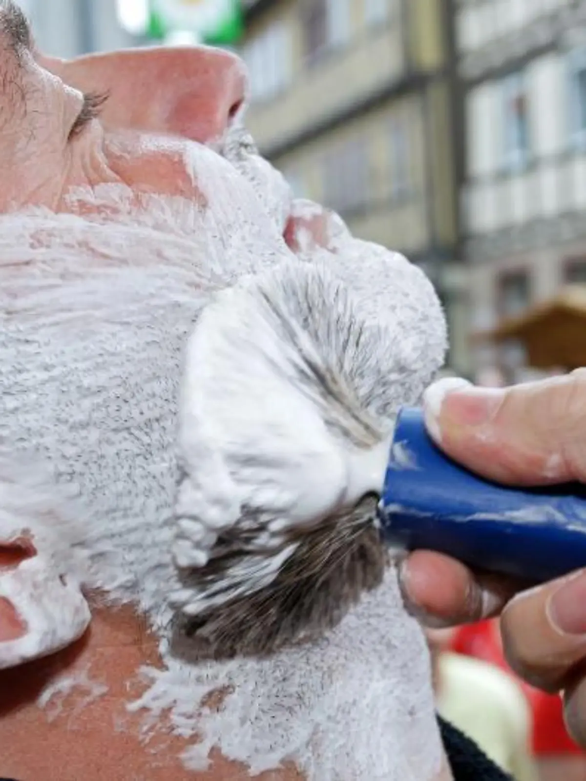 Ein Model wird am Sonntag (20.07.2008) bei einem Wettrasieren in Buchen im Neckar-Odenwald-Kreis mit einem Pinsel eingeseift. Bei einem Wettkampf vor dem Alten Rathaus haben sich mehr als 160 Bartträger von sechs Barbieren öffentlich rasieren lassen. Der Wettbewerb erinnert an ein historisches Ereignis vor 150 Jahren. Damals wurde ein Buchener vom Großherzog von Baden zum «König der Barbiere» gekrönt. Der 18.000-Einwohner-Ort im Neckar-Odenwald-Kreis hofft, mit dem schnellsten Nassrasierer ins Buch der Rekorde zu kommen. Foto: Ronald Wittek dpa/lsw +++(c) dpa - Bildfunk+++