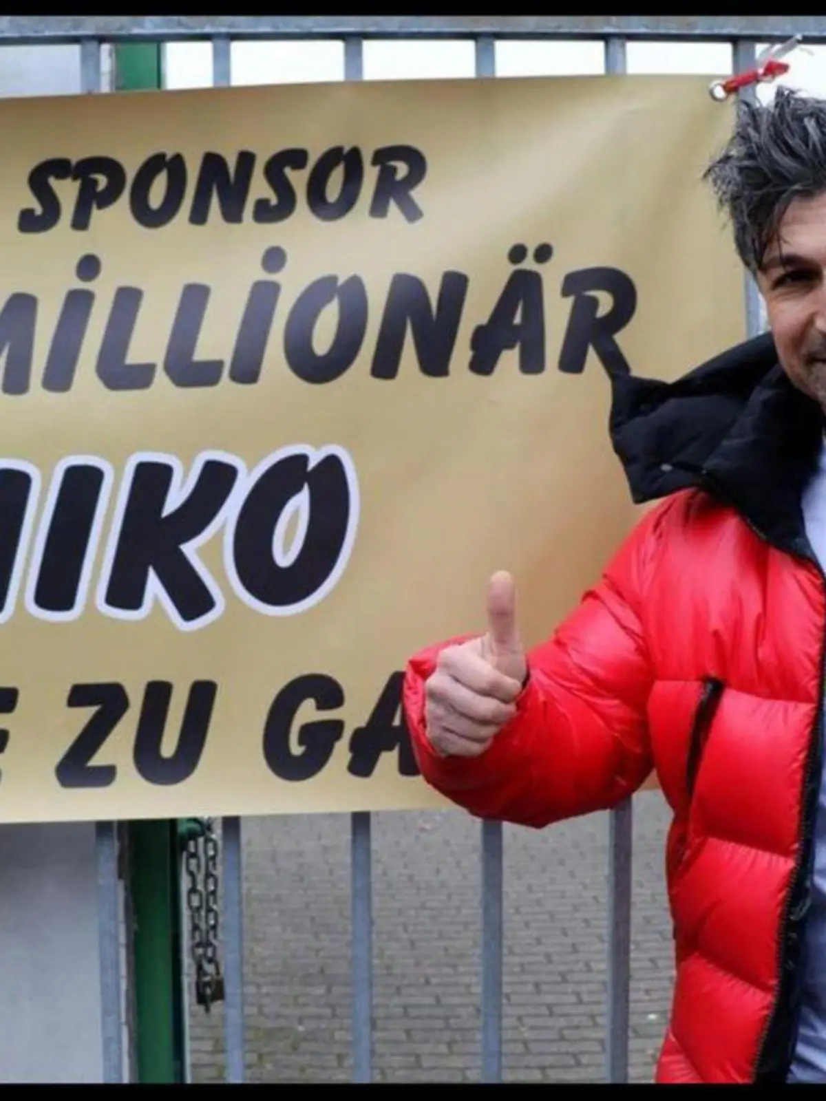Strahlend steht Chico vor dem Banner des Fußball-Vereins, das seine Anwesenheit ankündigt.