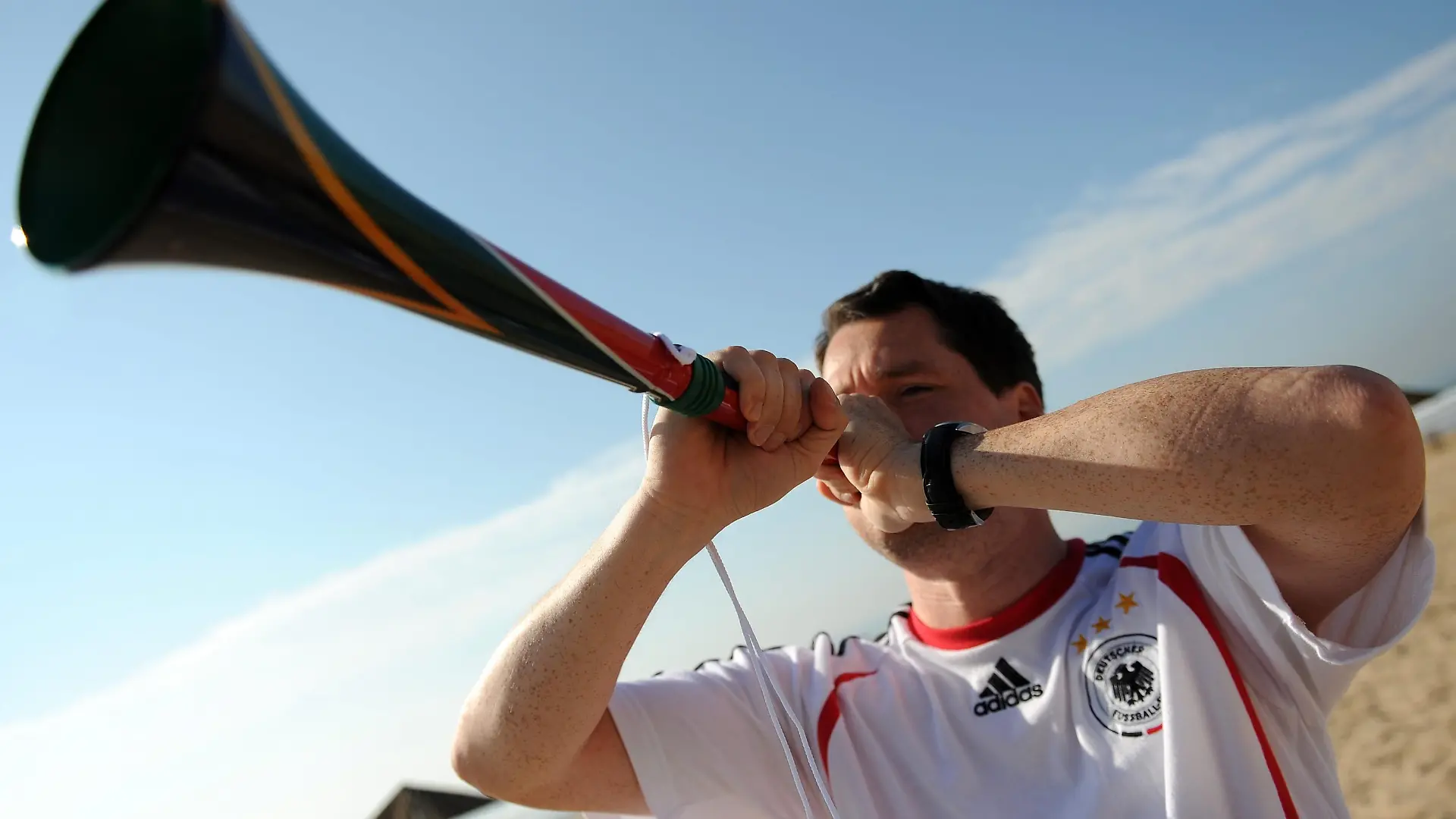 ARCHIV - Ein deutscher Fan bläst eine Vuvuzela beim Spiel Deutschland - Australien am 13.06.2010 in Durban Südafrika. Vuvuzelas sind der meistdiskutierte Fanartikel zur WM - und offensichtlich noch gefährlicher als gedacht: Ein einziger Fanfarenstoß aus der afrikanischen Tröte könne ausreichen,um das Gehör dauerhaft zu schädigen, warnt der Aalener Hörakustik-Professor Eckhard Hoffmann. Mit Ohrenschützern und einer schwarz-rot- goldenen Vuvuzela hat der Wissenschaftler eine menschengroße Plastik-Puppe beschallt. Sein Ergebnis: Im Gehörgang der Puppe kamen bis zu 160 Dezibel an. Schon ab 120 Dezibel kann ein kurzer Ton das Gehör schädigen. Bei dieser Lautstärke könnten nicht einmal mehr Lärm-Stöpsel die Ohren schützen, teilte der Experte am Dienstag (15.06.2010) mit. Foto: ANDY RAIN +++(c) dpa - Bildfunk+++