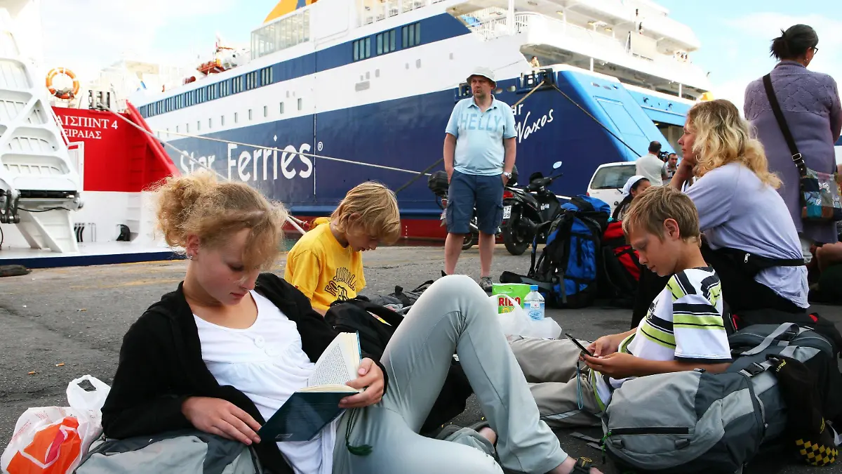 Tourists read in books at the port of Piraeus, Greece, as members of the communist's labour union (PAME) prevent them from embarking on ferries heading to Aegean islands on 23 June 2010. All Greek-flag ships remained at port in Piraeus due to a 24-hour strike of the seamen in protest against the government's plan to lift cabotage (the transport of goods or passengers between two points in the same country) restrictions, which will allow foreign cruiseships to use the Greek sea routes and ports. The leftist PAME union called the sailor?s strike to protest the government?s austerity plans. A court had declared the strike illegal on 22 June 2010. EPA/KATERINA NOMIKOU  +++(c) dpa - Bildfunk+++