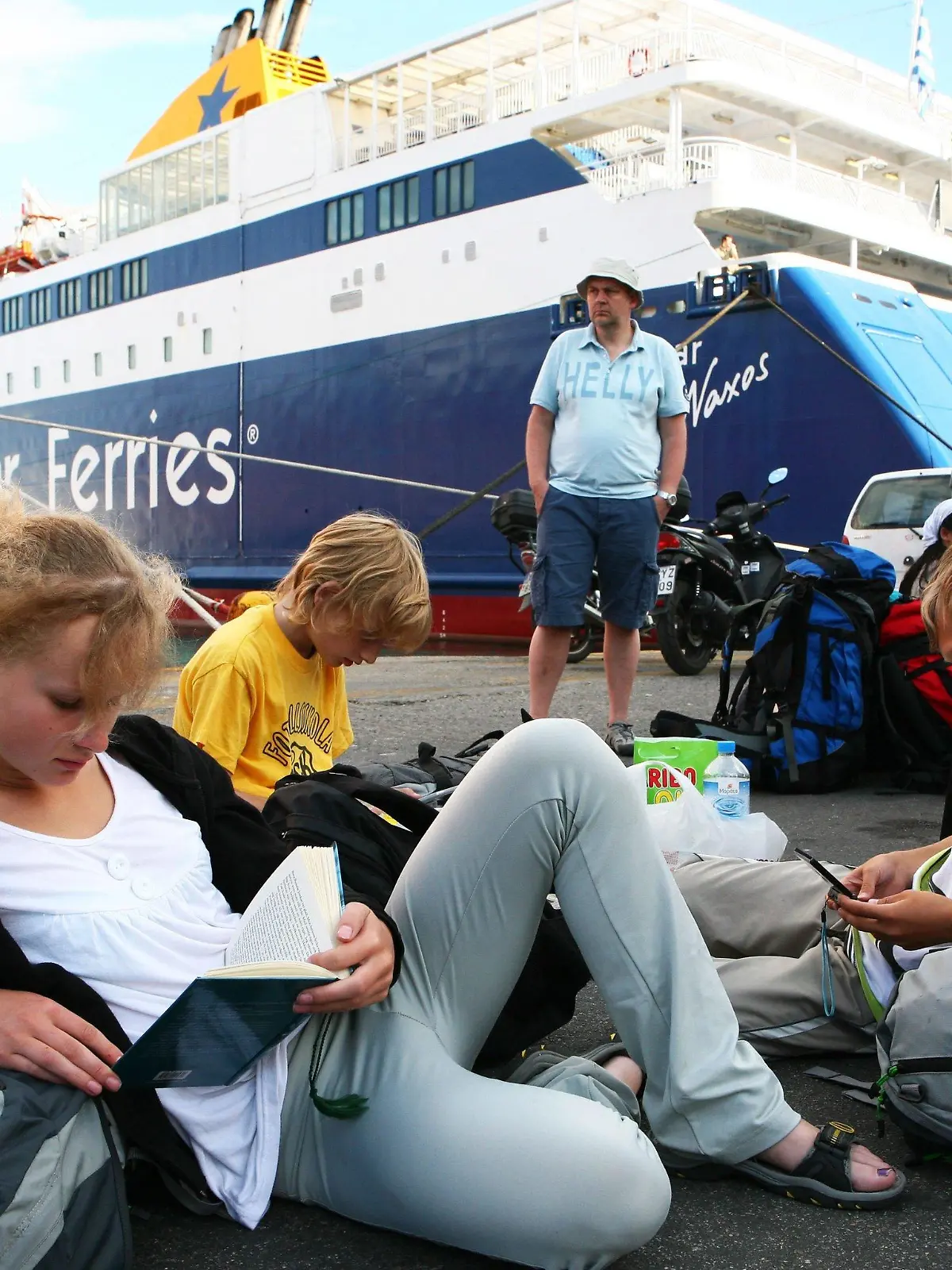 Tourists read in books at the port of Piraeus, Greece, as members of the communist's labour union (PAME) prevent them from embarking on ferries heading to Aegean islands on 23 June 2010. All Greek-flag ships remained at port in Piraeus due to a 24-hour strike of the seamen in protest against the government's plan to lift cabotage (the transport of goods or passengers between two points in the same country) restrictions, which will allow foreign cruiseships to use the Greek sea routes and ports. The leftist PAME union called the sailor?s strike to protest the government?s austerity plans. A court had declared the strike illegal on 22 June 2010. EPA/KATERINA NOMIKOU  +++(c) dpa - Bildfunk+++
