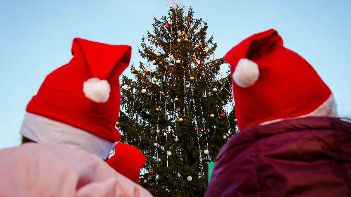 18.12.2019, Ukraine, Uzhhorod: Zwei Kinder mit roten Mützen stehen vor dem rund 14 Meter hohen Weihnachtsbaum im Stadtzentrum. Foto: Ukrinform/dpa +++ dpa-Bildfunk +++