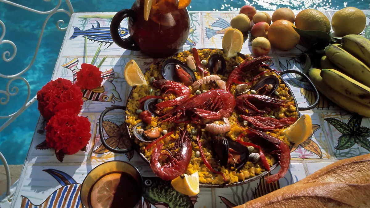 Wie im Urlaub: Eine Pfanne des spanischen Reisgerichts Paella reichlich belegt mit Meeresfrüchten, dazu leckeres Weißbrot und Sangria mit frischen Früchten. Aufnahme von 1992.