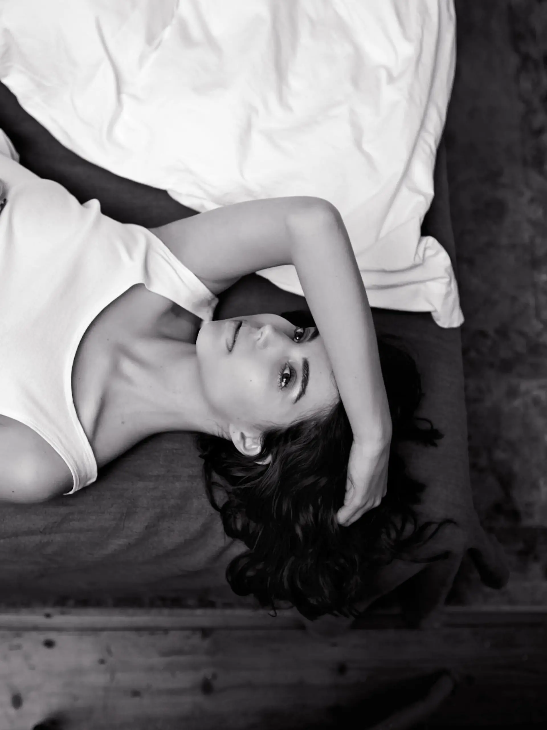 High angle shot of a young woman lying on her bed in black and white