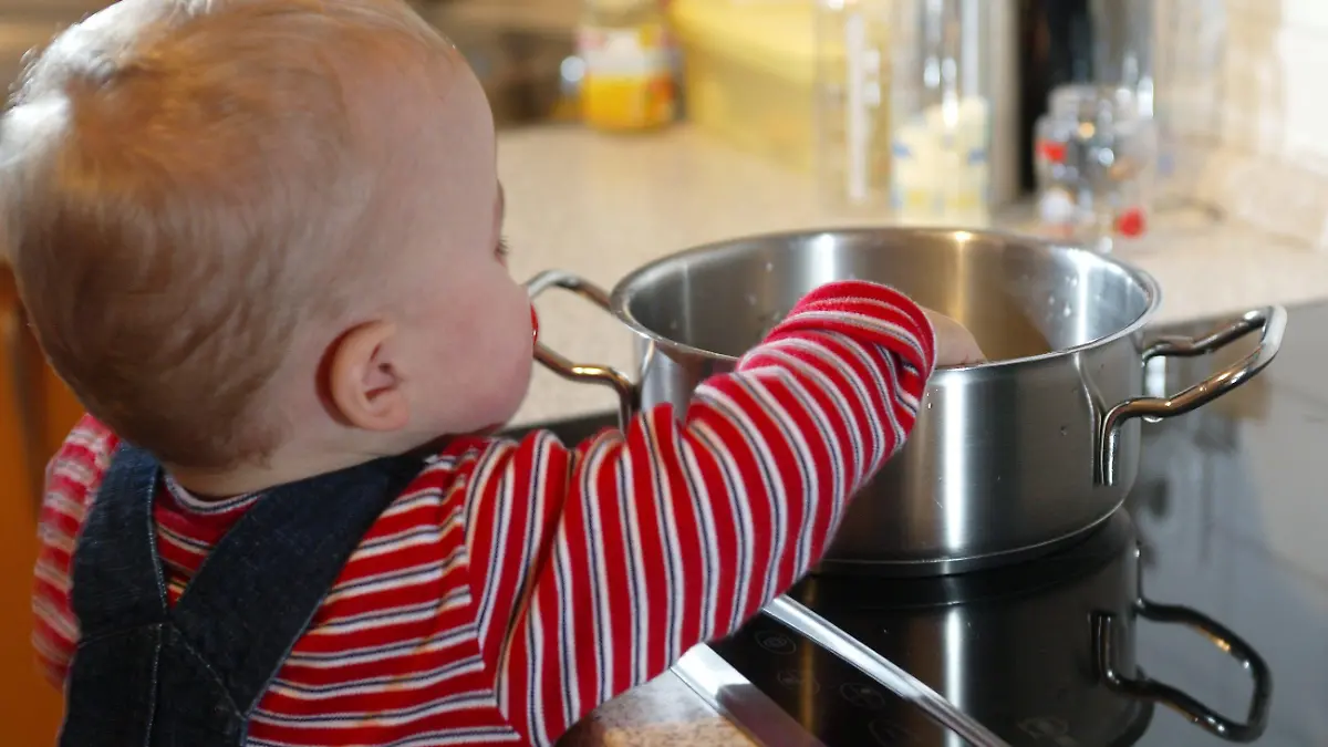 Gefahren für Kleinkinder im Haushalt. Die Neugier und das Spielbedürfnis von Kindern führen immer wieder zu Unfallgefahren im Alltag. Schon ein kurzer unbeobachteter Moment kann schwere Folgen haben. Es besteht erhöhte Aufsichtspflicht. Hier: Kleiner Junge spielt mit einem Kochtopf auf dem Küchenherd. Es besteht die Gefahr von Verbrühungen und Verbrennungen durch heisses Wasser oder Fett. Troisdorf, Nordrhein-Westfalen, Deutschland, 25.10.2005