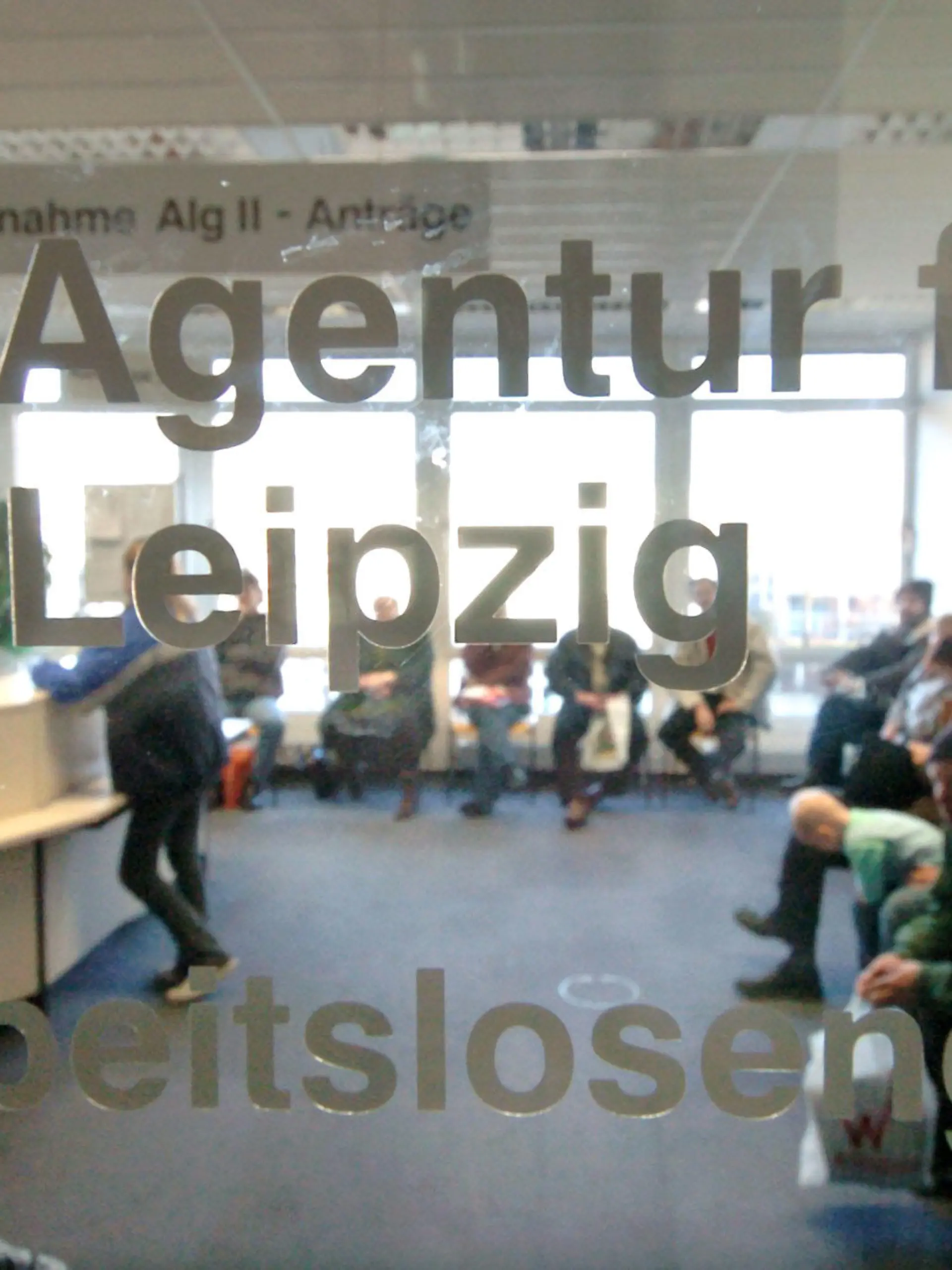 Hinter einer Glasscheibe einer Agentur für Arbeit in Leipzig herrscht am Dienstag (28.12.2004), dem offiziellen vorletzten Öffnungstag in diesem Jahr, noch großer Andrang bei der Antragsannahme für Arbeitslosengeld II. Im Bereich der Arbeitsagentur in Leipzig wurden in den letzten zwei Monaten rund 40.000 Bescheide an Antragsteller für ALG II herausgeschickt. Ab Januar 2005 erhalten in Deutschland Bezieher der bisherigen Arbeitslosenhilfe sowie arbeitsfähige Sozialhilfempfänger das neue Arbeitslosengeld II. Foto:Waltraud Grubitzsch/lsn +++(c) dpa - Bildfunk+++