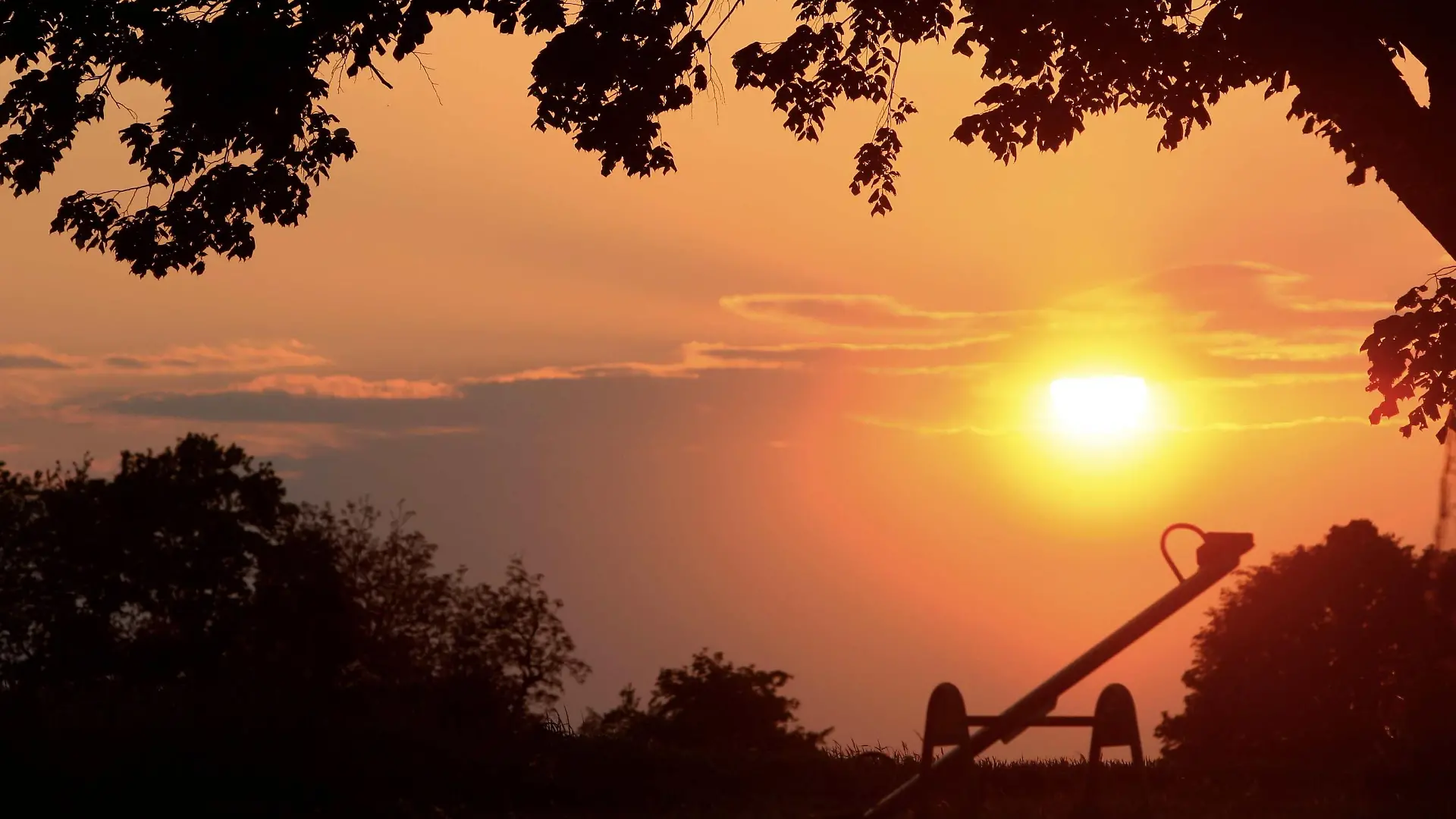 Die Sonne geht am Mittwoch (14.05.2008) hinter einer Kinderwippe bei Lichtenfels (Oberfranken) auf. Laut Wettervorhersage soll ab Donnerstag regnerisch und etwas kühler werden. Foto: Marcus Führer dpa/lby +++(c) dpa - Bildfunk+++