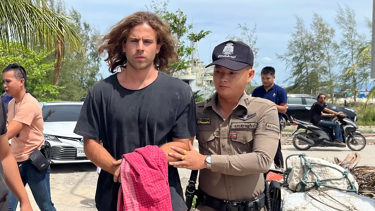 A Thai police officer escorts Spanish Daniel Sancho Bronchalo on suspicion of murdering and dismembering a Colombian surgeon from Koh Phagnan island to Koh Samui Island court, southern Thailand, Monday, Aug. 7, 2023. Sancho, the son of two Spanish film stars, has been arrested in Thailand on suspicion of murdering and dismembering Edwin Arrieta Arteaga on a tourist island, police said. Sancho was taken from Koh Phagnan, where the remains of the Colombian surgeon were found, to another island, Samui, where he is being held, Surat Thani provincial police commander Saranyu Chamnanrat said Tuesday. (AP Photo/Somkeat Ruksaman)