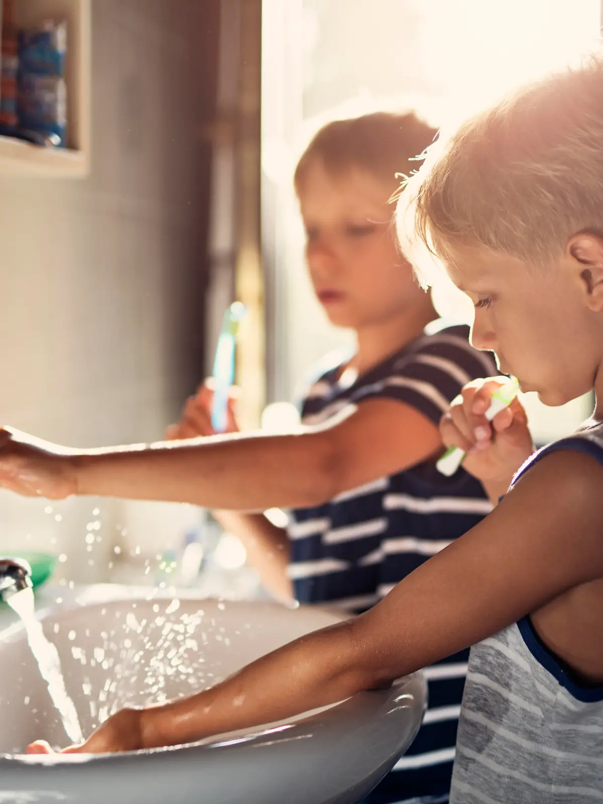 Two boys aged 8 are brushing teeth together in a bathroom.
