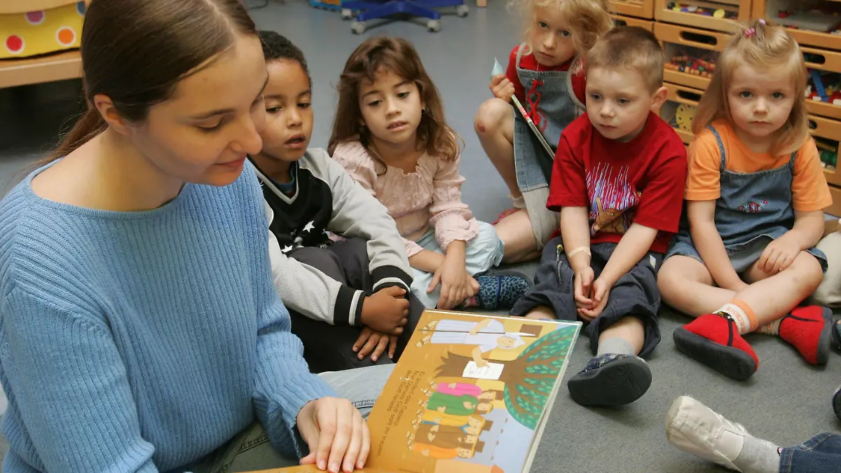 Lesepatin Anja Ziegler (l) liest im Karlsruher katholischen Kindergarten St. Albert Kindern aus einem Buch vor (Foto vom 20.07.2005). Die Aktion geht auf eine Initiative der Stadt Karlsruhe zurück. Gemeinsam mit dem Aktivbüro, dem Kulturamt und der Stadtbibliothek entwickelte sie seit dem Jahr 2003 ein Konzept zur Einrichtung von Lesepatenschaften. Mittlerweile lesen über 120 Lesepaten ehrenamtlich in Kindergärten und Kindertagesgaststätten, Schulen und Bibliotheken vor. Foto: Uli Deck (zu dpa/lsw-KORR: "Leselust statt Lesefrust - Lesepaten sollen zu den Büchern locken" vom 24.07.2005) +++(c) dpa - Bildfunk+++