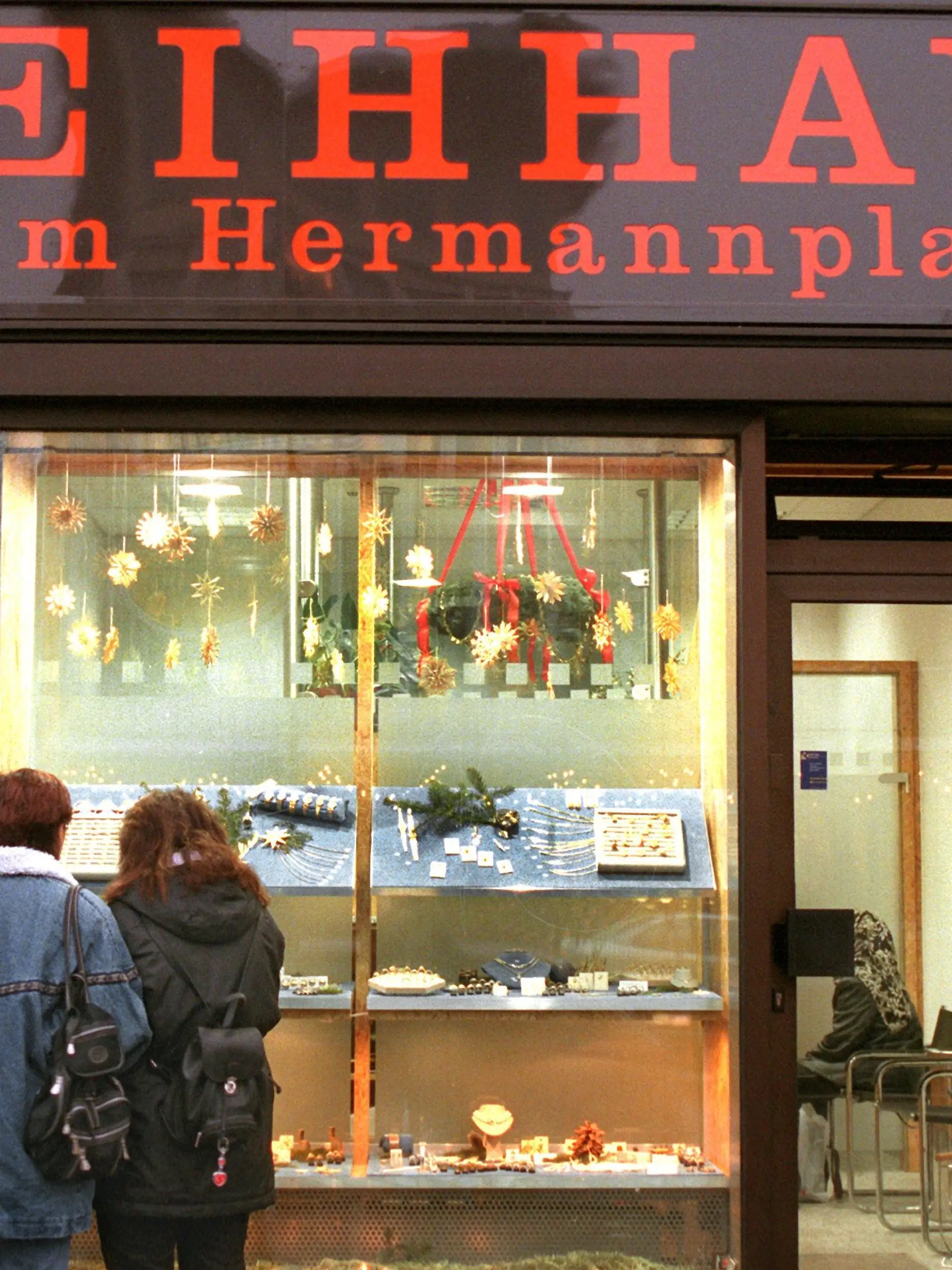 Passanten betrachten am 16.12.1998 die Auslagen im Schaufenster eines Leihhauses in Berlin-Kreuzberg. Besonders in der Vorweihnachtszeit herrscht reges Treiben in den Pfandleihen der Hauptstadt. Gegen Bares werden hier Videorekorder und Fotoapparate getauscht, Uhren und Halscolliers, Besteck und Stereoboxen, Gold oder Silber - vom schlichten Konfirmationsschmuck bis zu schweren Erbstücken. Viele Menschen holen mit dem Weihnachtsgeld ihr Eigentum wieder ab, während sich andere von ihren besten Stücken trennen, um Bargeld für die Festgeschenke zu erhalten. Während die Umsätze der Pfandleiher deutschlandweit um moderate drei Prozent pro Jahr steigen, verzeichnen die 14 Berliner Betriebe schätzungsweise doppelt soviel Wachstum.