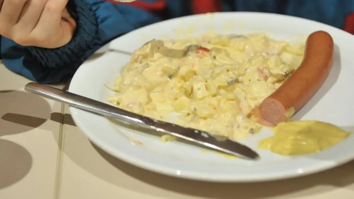 Auf einem Teller sind Kartoffelsalat und Würstchen angerichtet